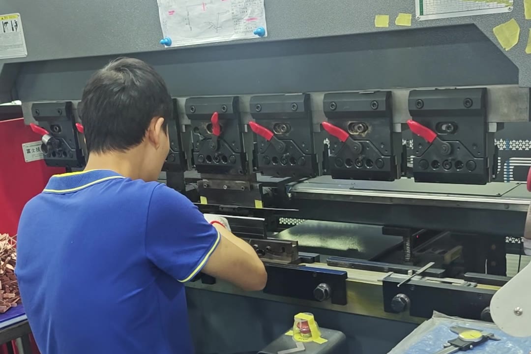 Operator bending copper sheet-metal parts on a CNC press brake